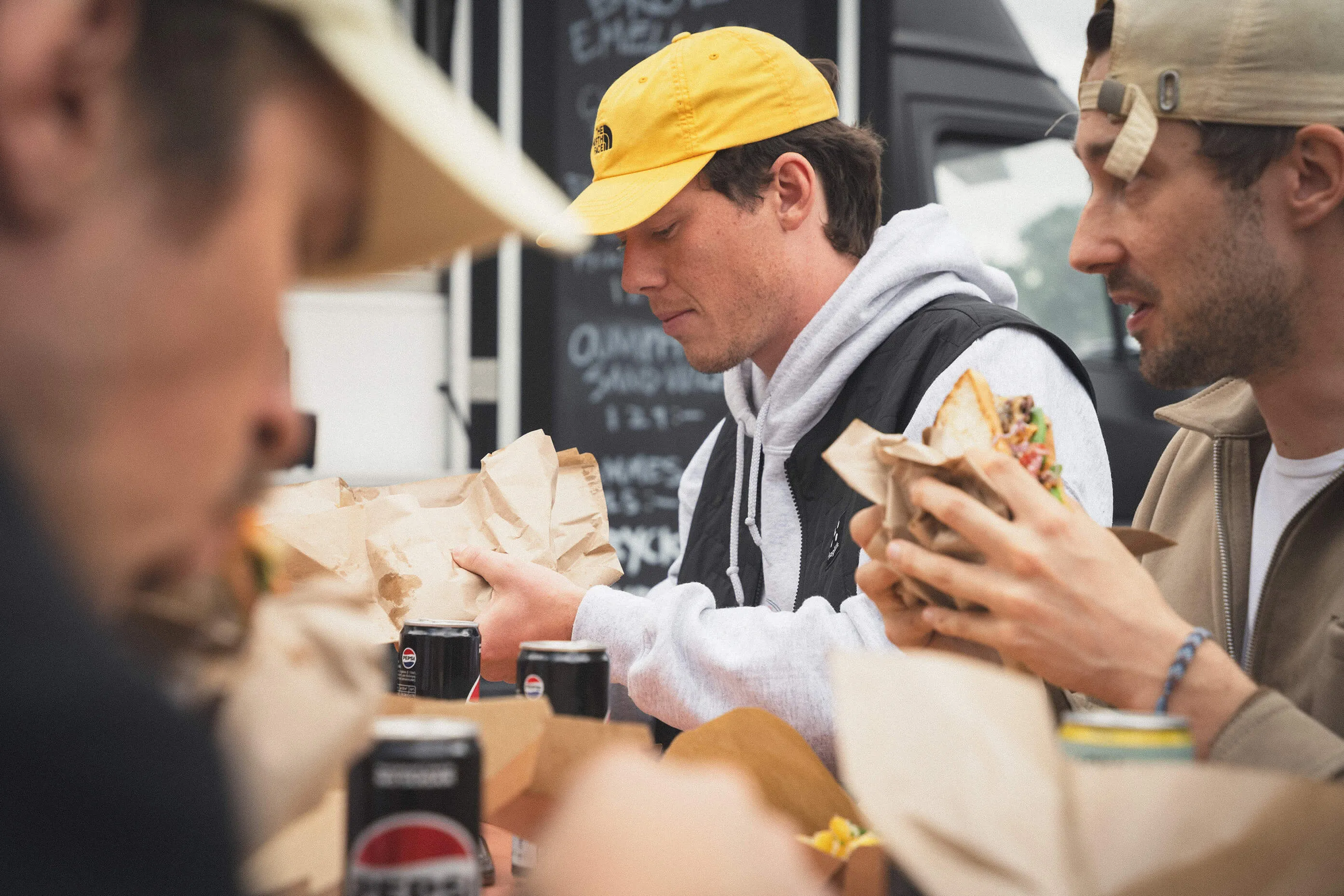 Kollegor äter nylagade mackor tillsammans vid foodtrucken under ett företagsevent