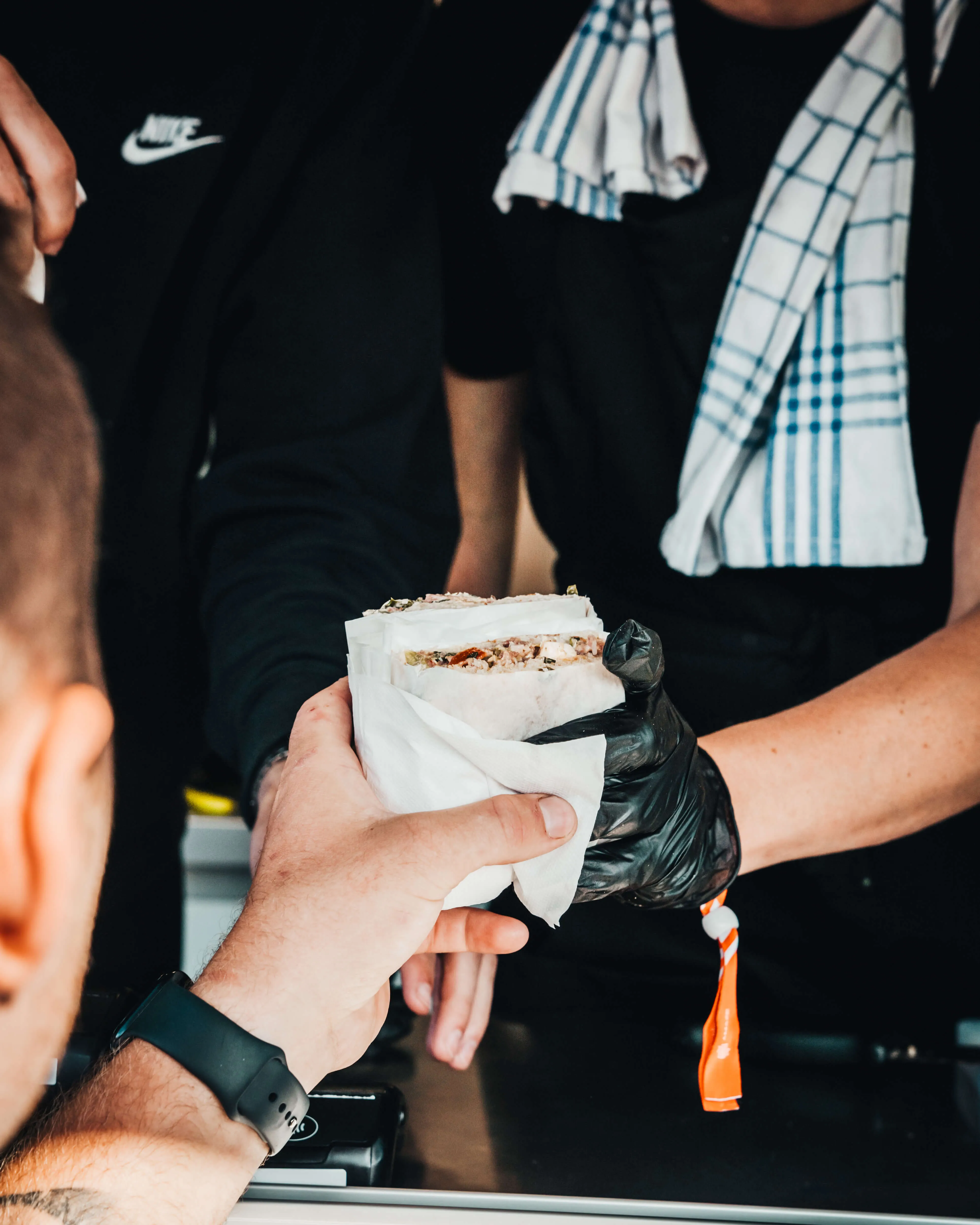 En nylagad macka räcks över serveringsdisken till en gäst vid foodtrucken