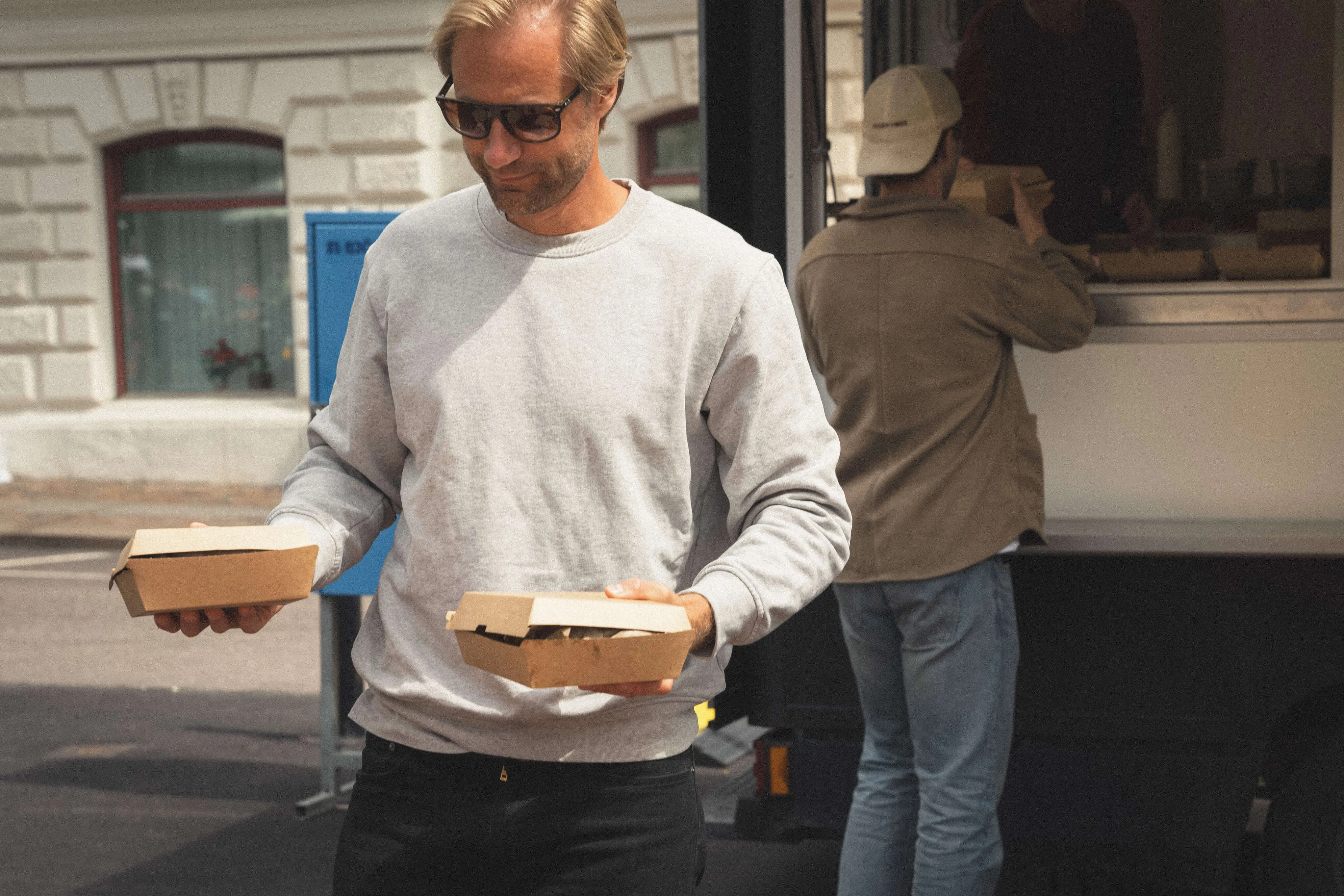 Gäst hämtar take away-boxar med nylagade mackor vid foodtruckens lucka